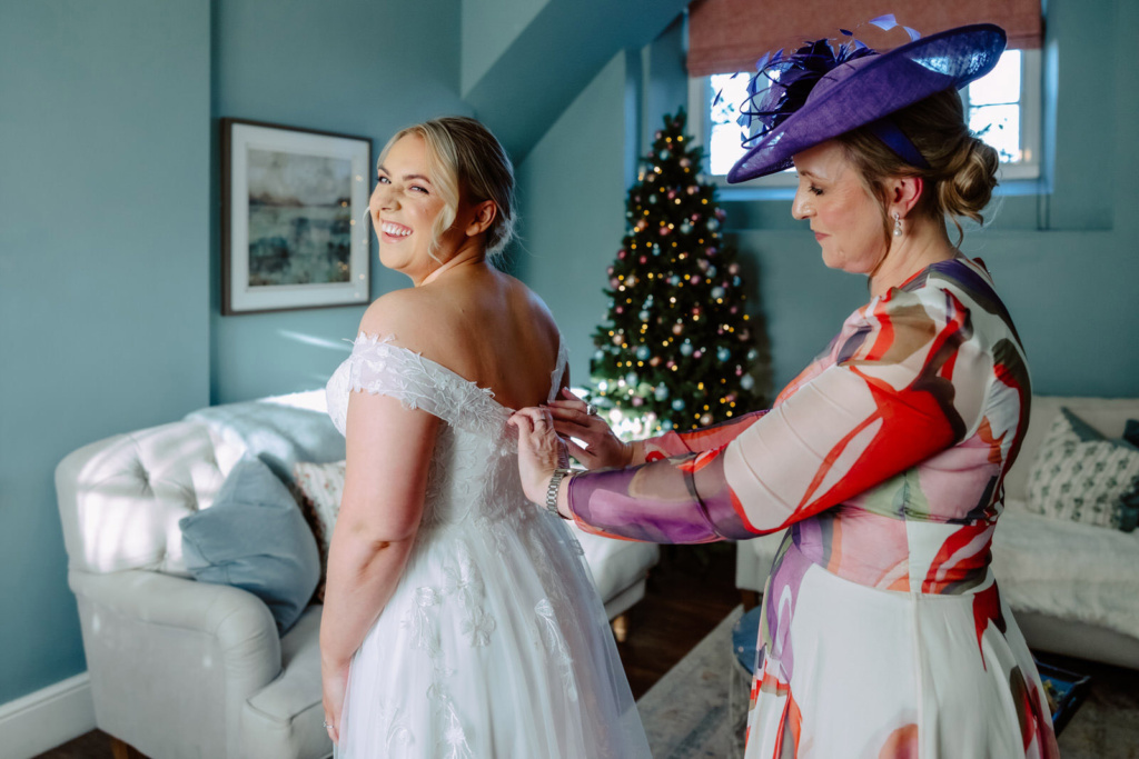 A bride helping her mother put on her wedding dress at Tower House at Rowton Castle.