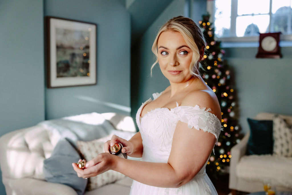 A bride applies her perfume in front of a christmas tree.