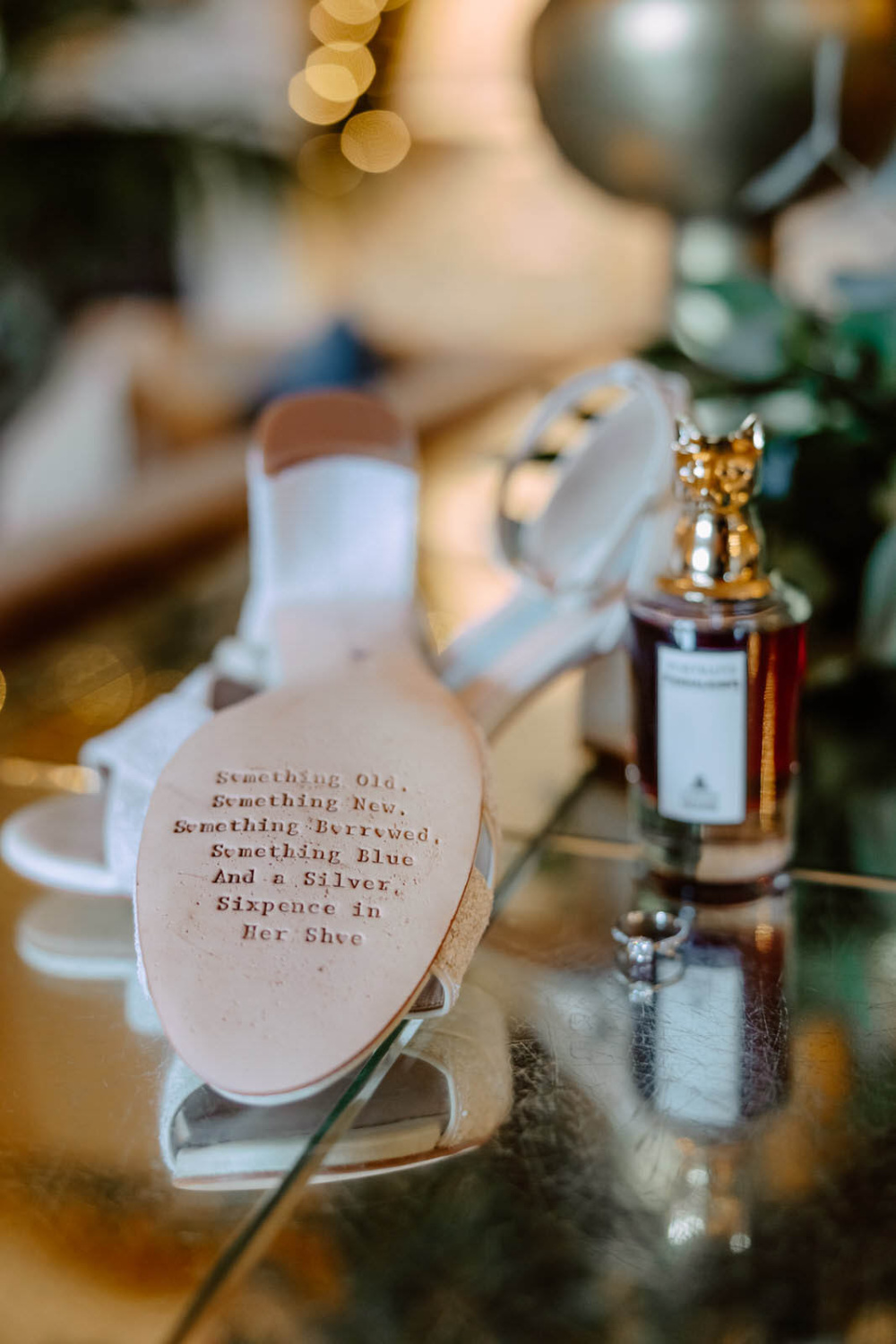 A pair of bride's shoes and a bottle of perfume on a table.