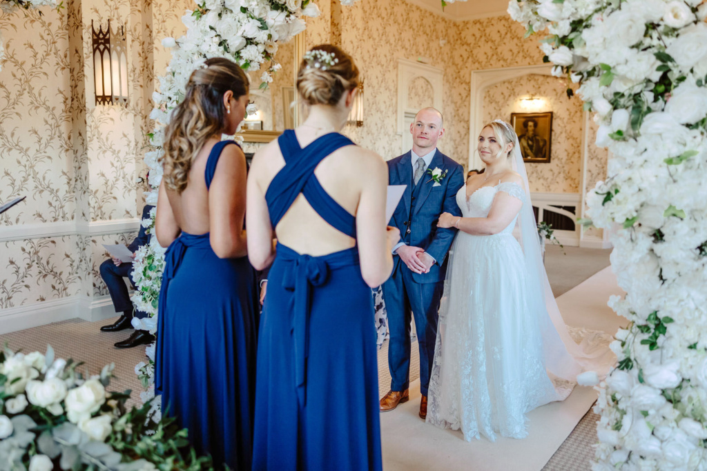 A bride and groom stand in front of an archway during their wedding ceremony at Rowton Castle.