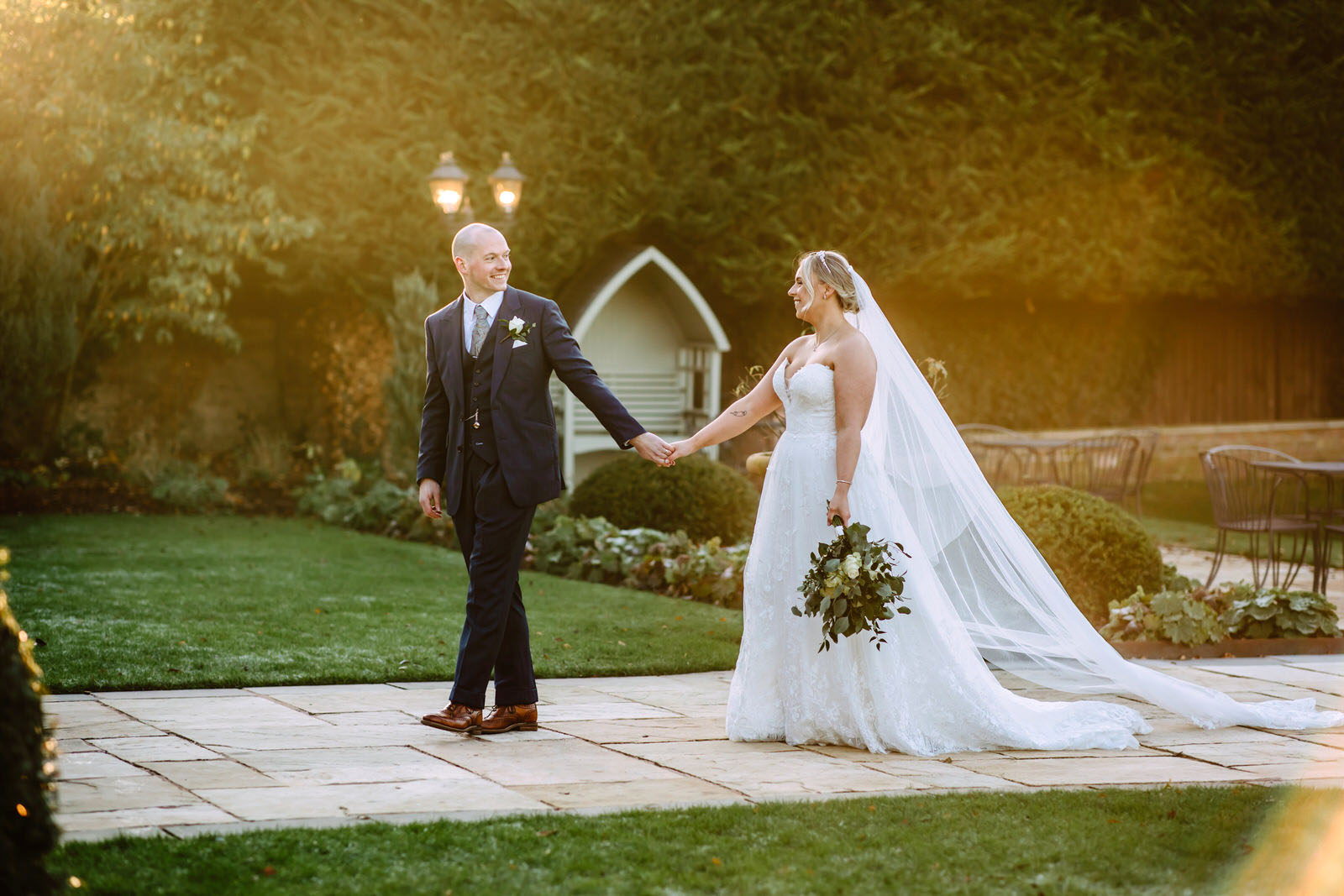 A bride and groom holding hands in a garden at Rowton Castle wedding