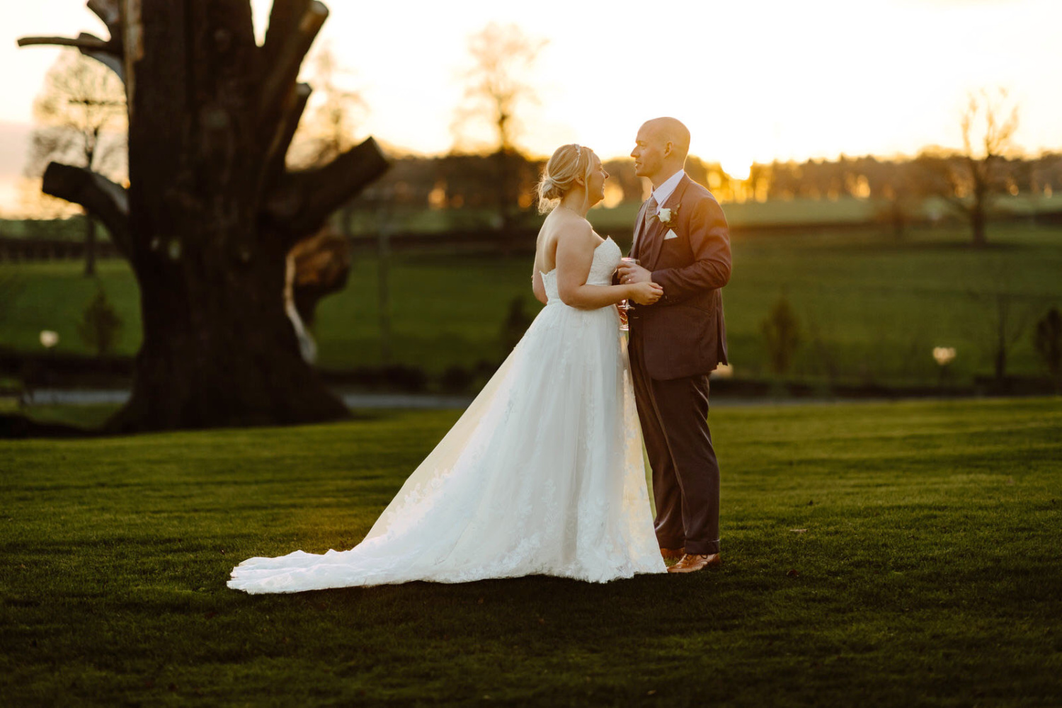 The Bride and the groom posing for the portraits at garden at Rowton Castle with a beautiful sunset at the background.