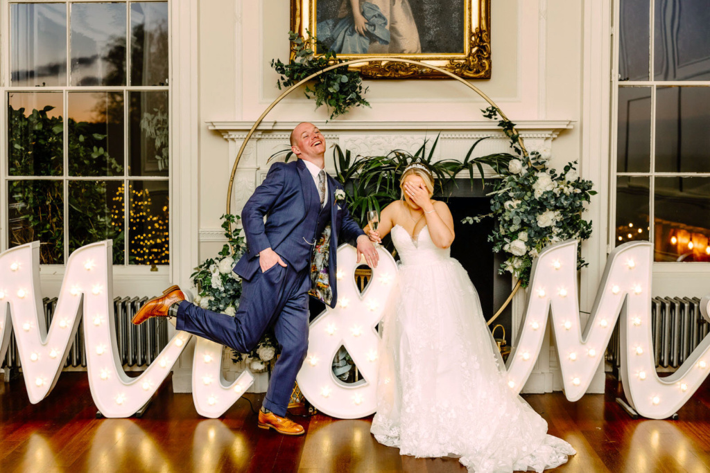 A bride and groom posing in front of the letters mr and mrs.