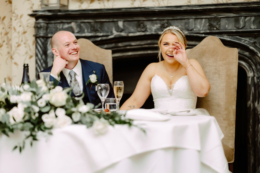 A bride and groom laughing at their wedding reception.