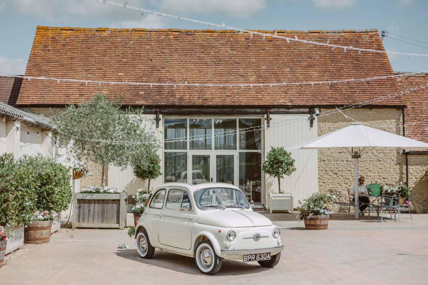 A fiat 500 parked in front of a Stratton Court Barn wedding photographer.