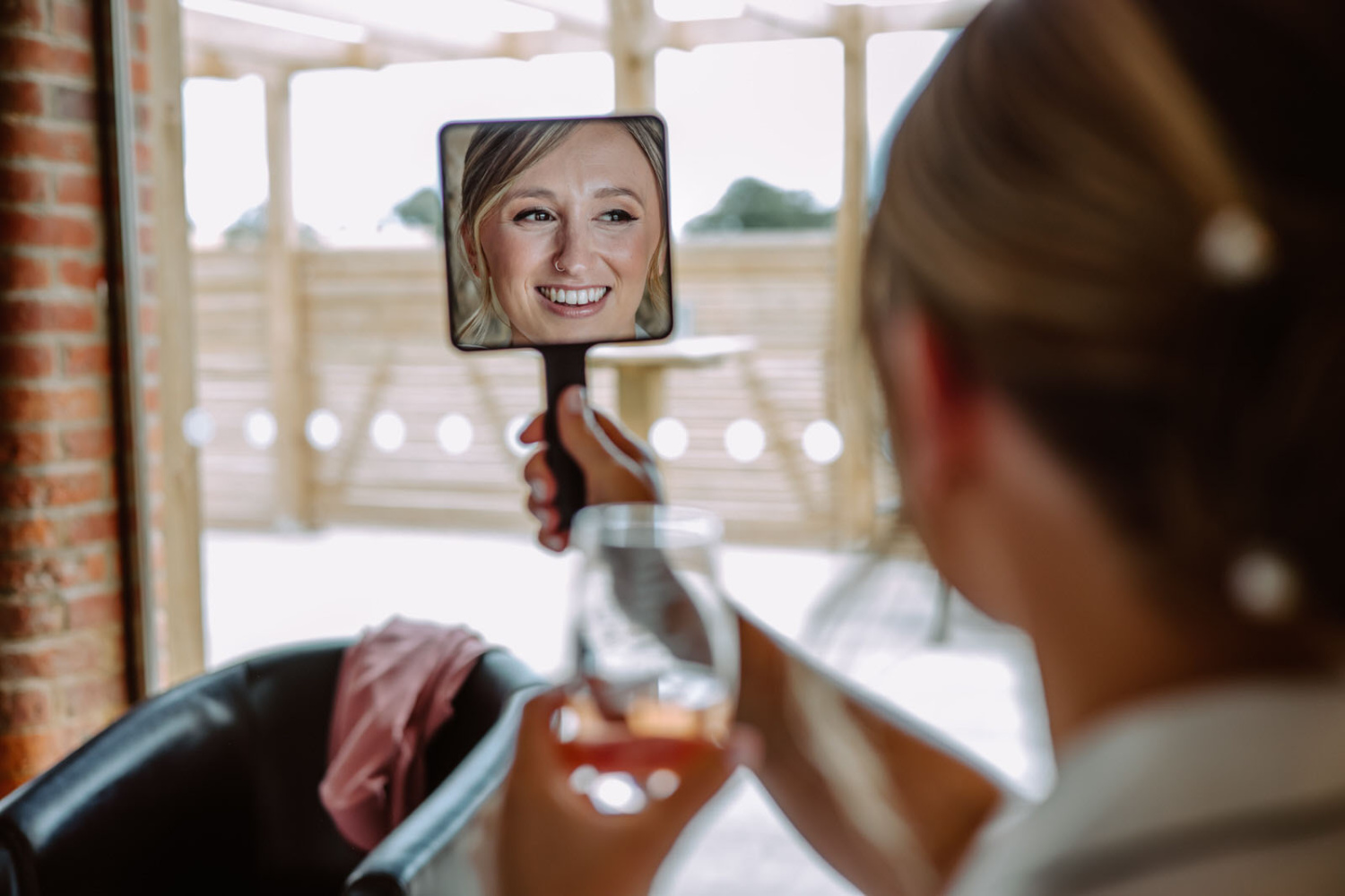 A bride holding a glass of wine in front of a mirror.
