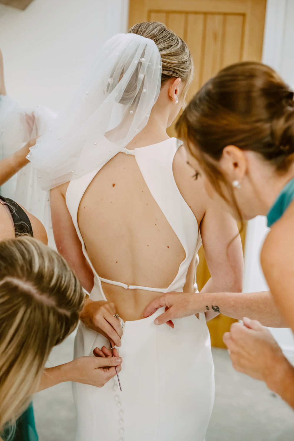 Bridesmaids helping the bride with their wedding dresses.