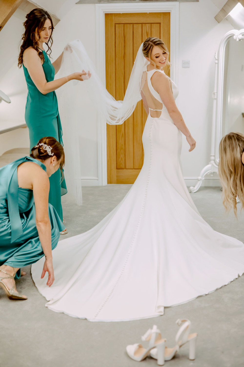 A bride getting ready in her wedding dress with her bridesmaids.