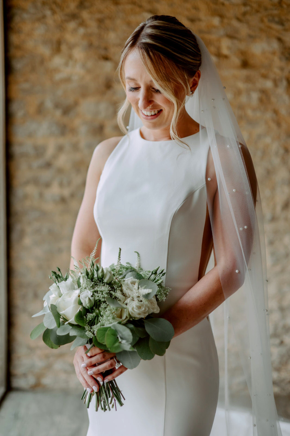 A bride in a white wedding dress holding a bouquet at Stratton Court Barn.