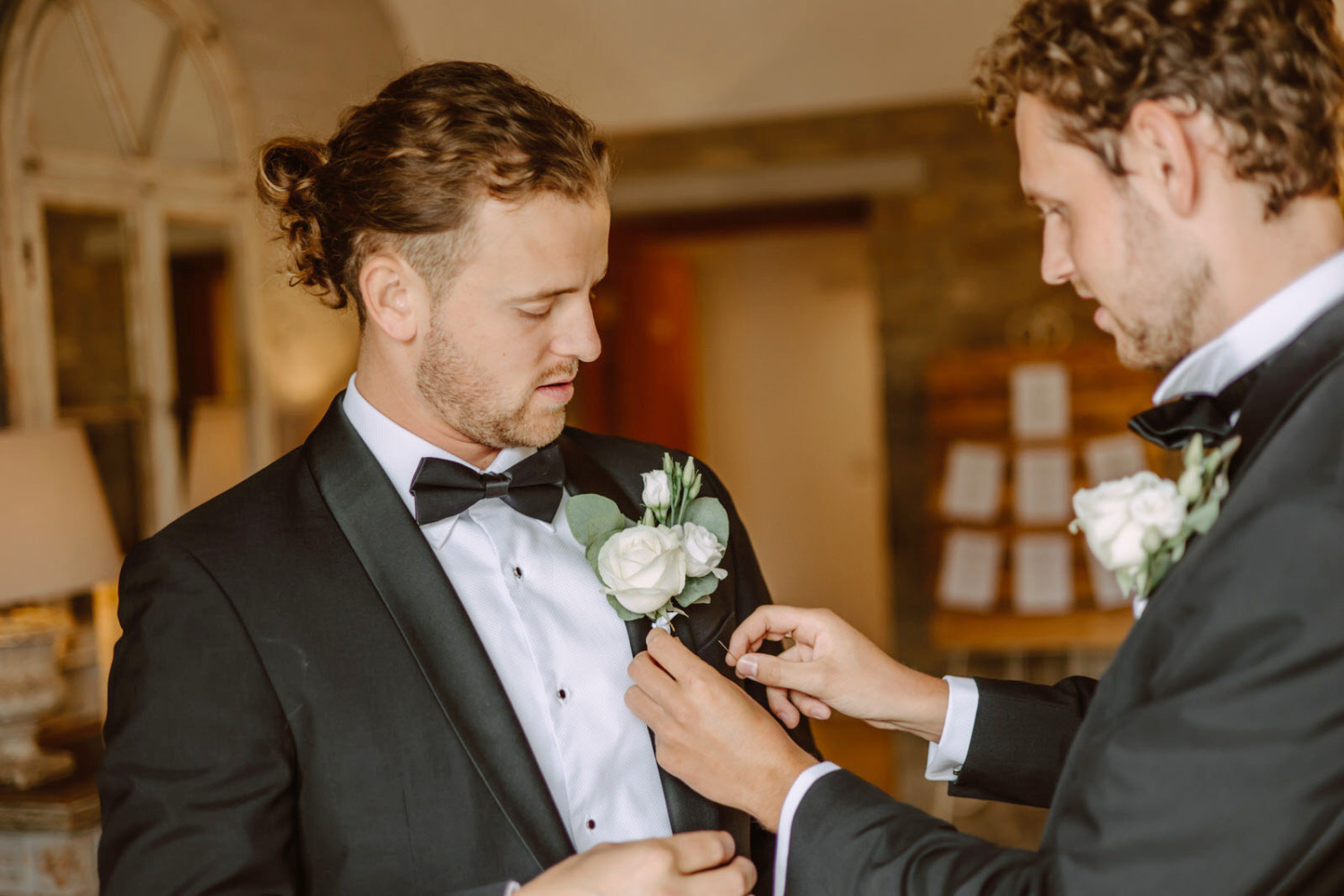 The best man place a buttonhole for the groom.