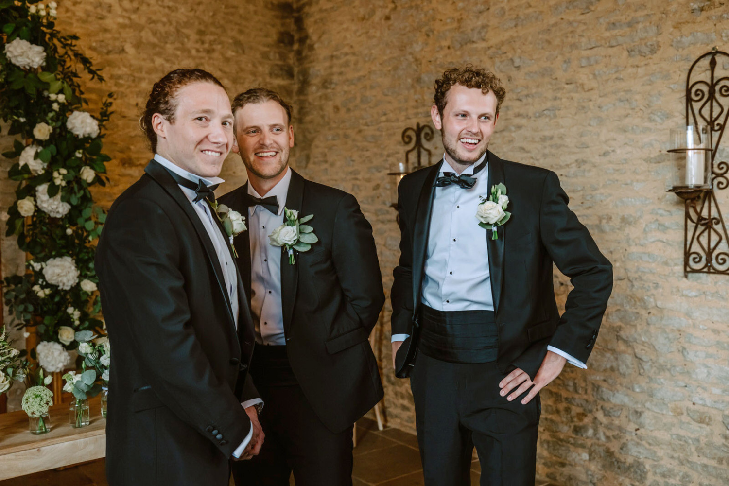 Three groomsmen in tuxedos standing next to each other.