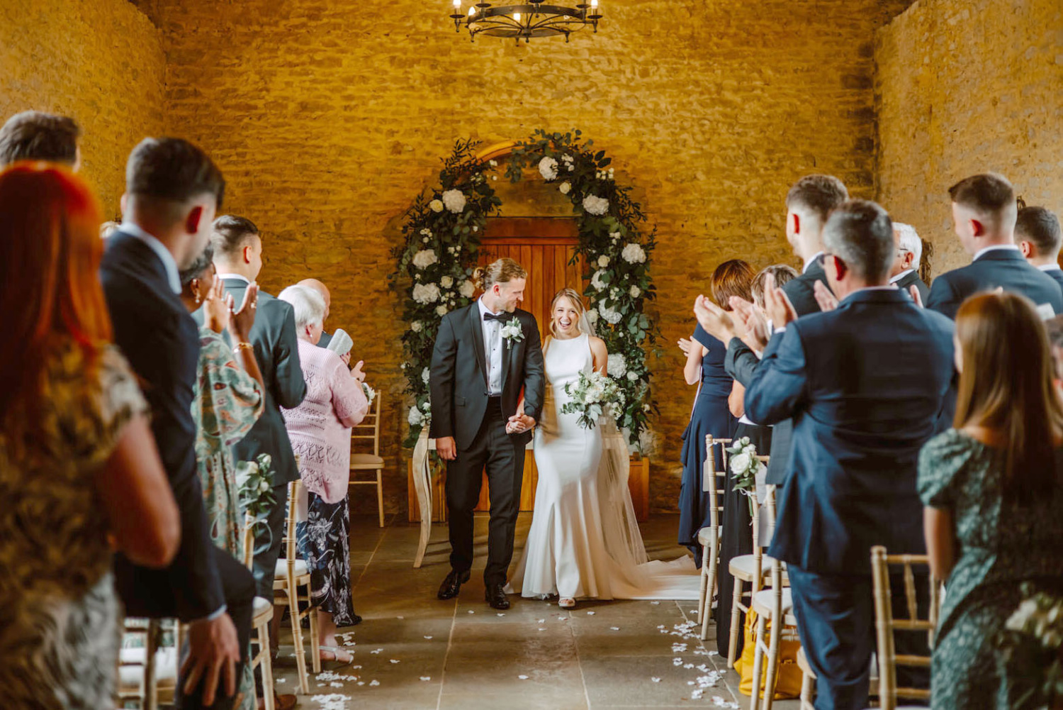 A bride and groom walking down the aisle at their wedding ceremony Stratton Court Barn.