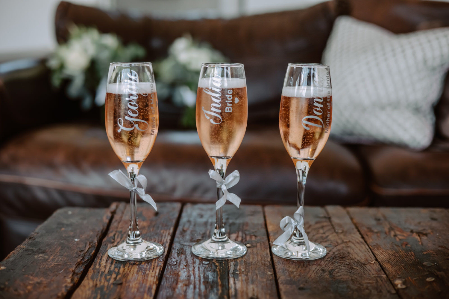 Three champagne flutes are sitting on a table next to a couch.