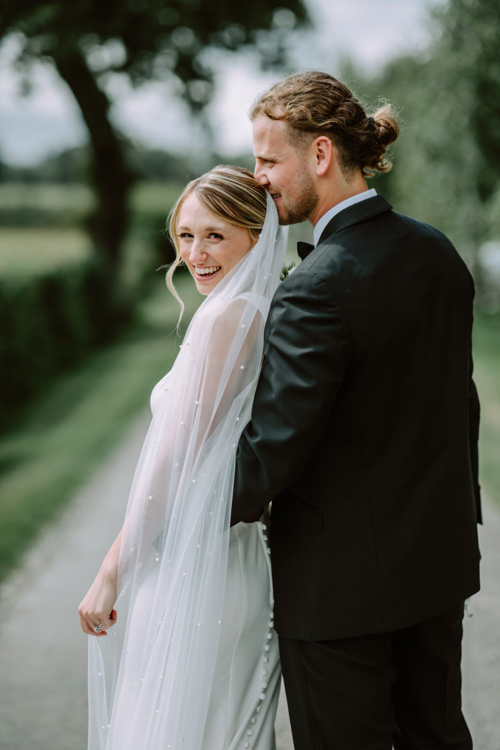 A bride and groom embracing on a path.