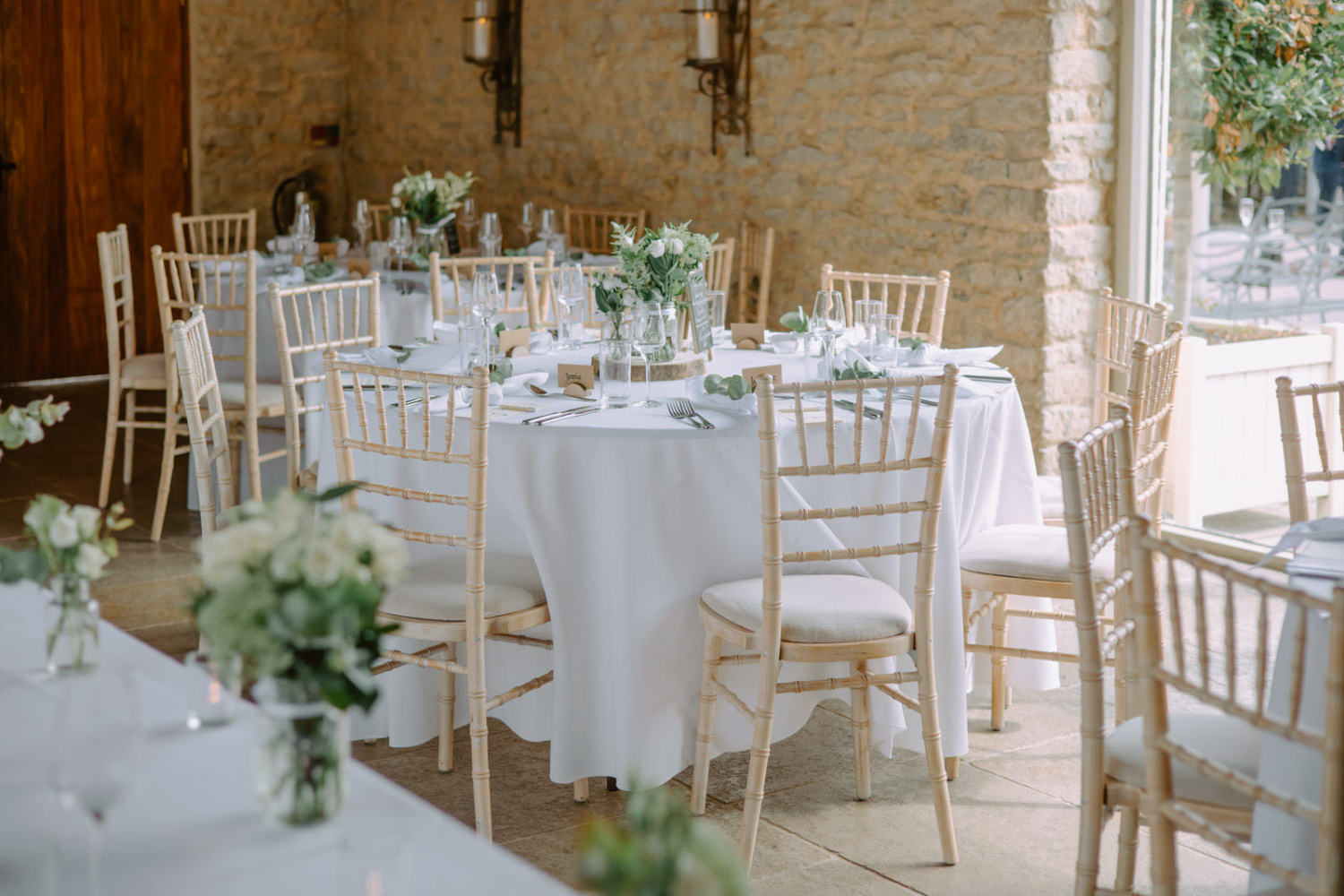 A wedding reception set up with white tables and chairs.