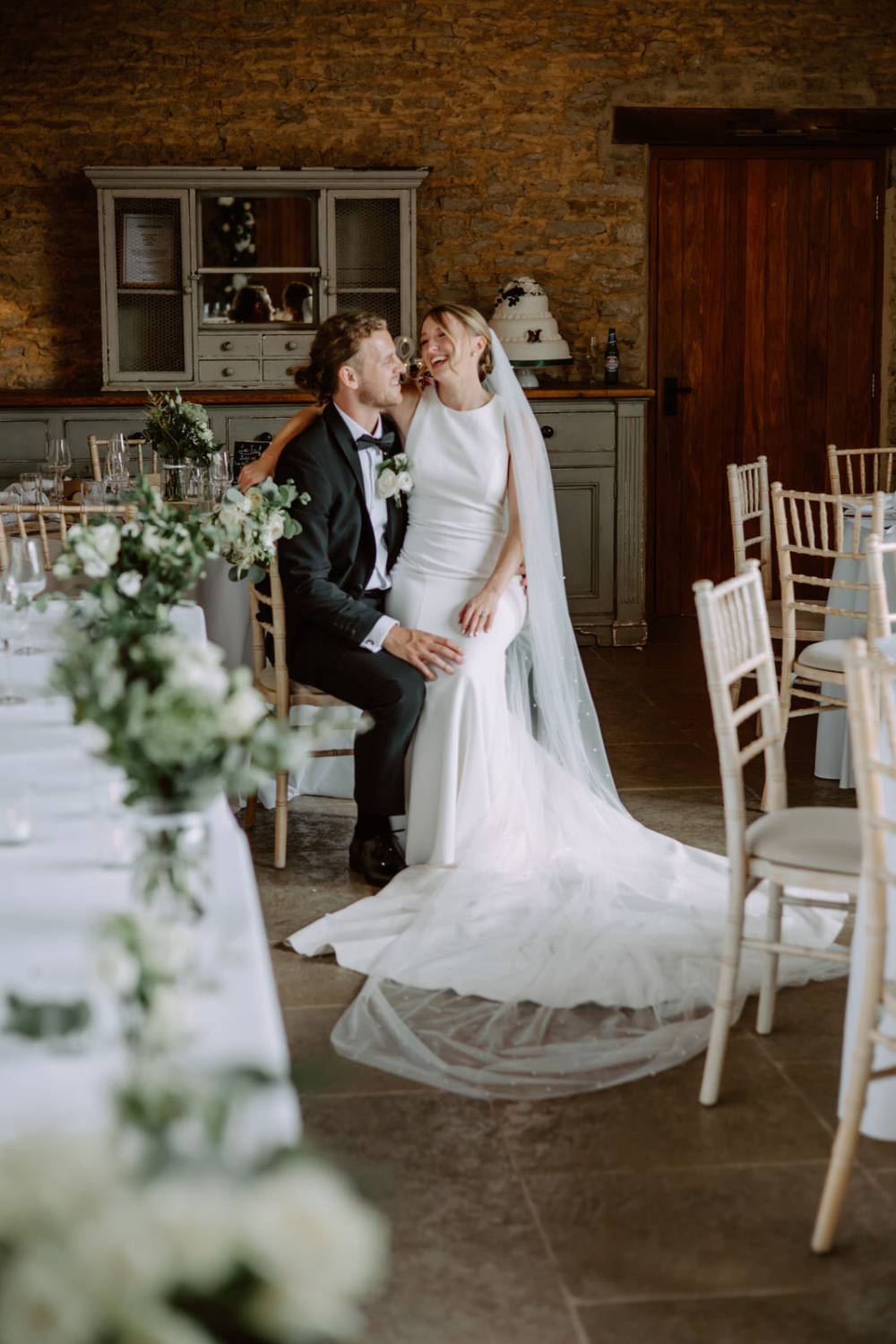 A bride and groom sitting at a table in a Stratton Court barn.