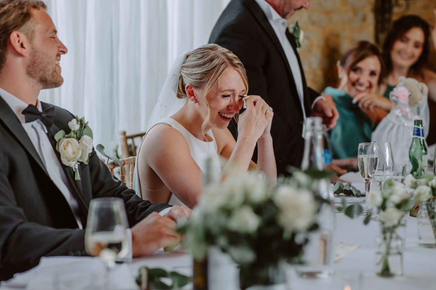 A bride and groom laughing at their wedding reception.