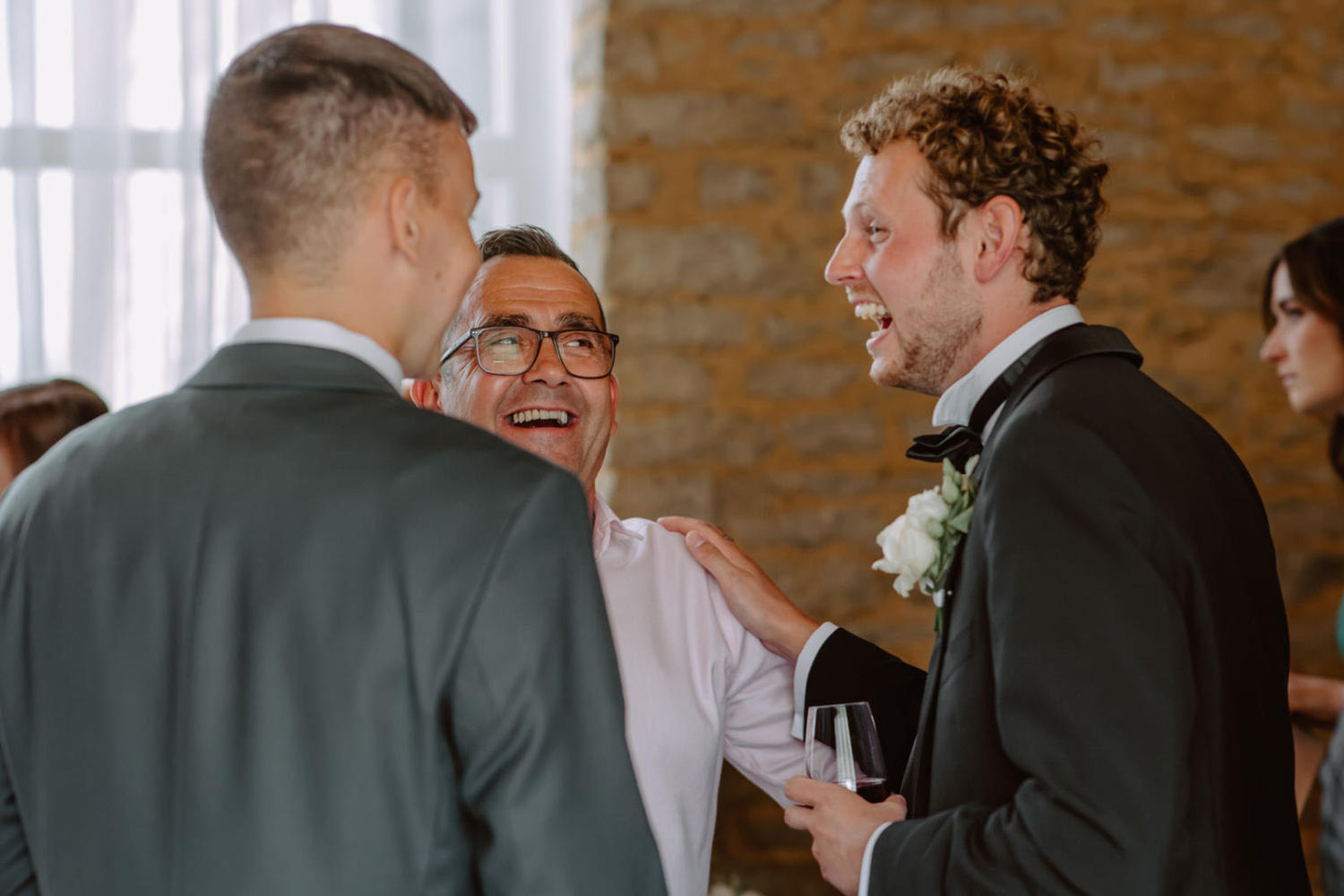 A group of men laughing at a wedding reception.
