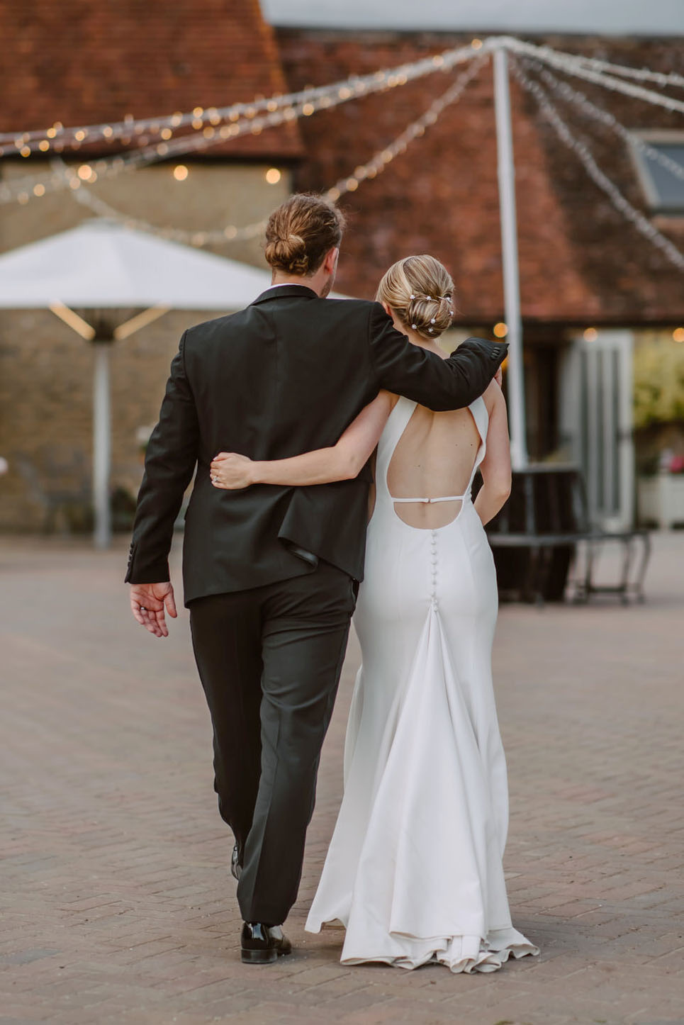 A bride and groom walking down a courtyard at a wedding Stratton Court Barn.