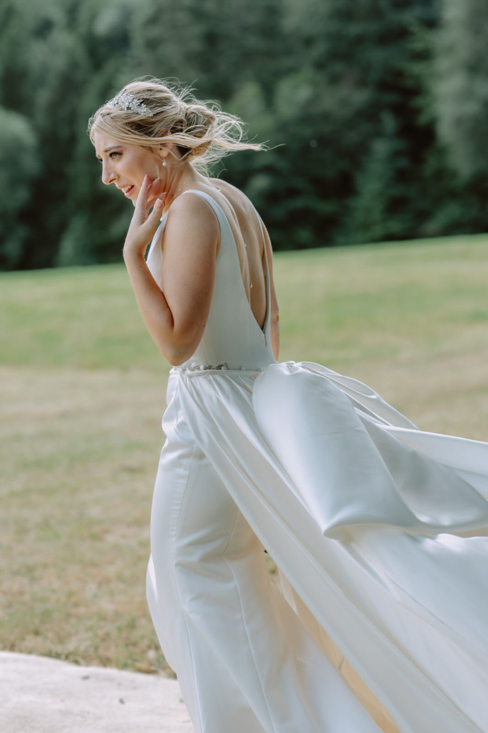 A bride in a white wedding dress walking through a field.