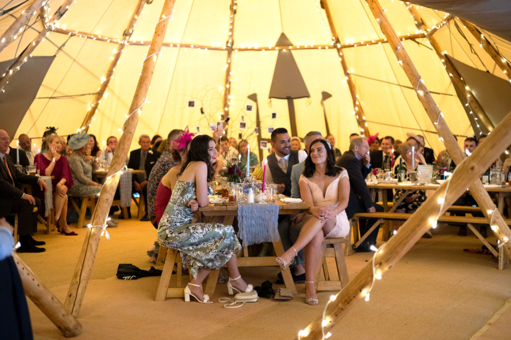 A group of people sitting in a Tipi at a wedding reception.