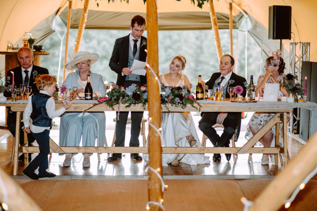 A group of people sitting at a table in a tent.