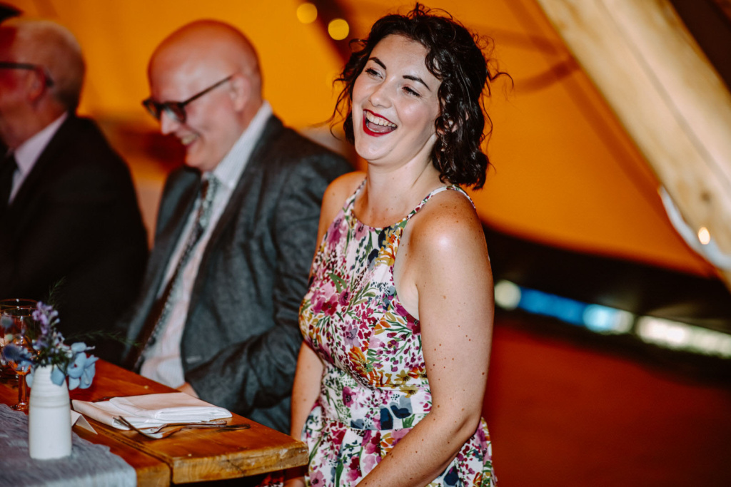 A woman laughing at a wedding reception in a tipi.