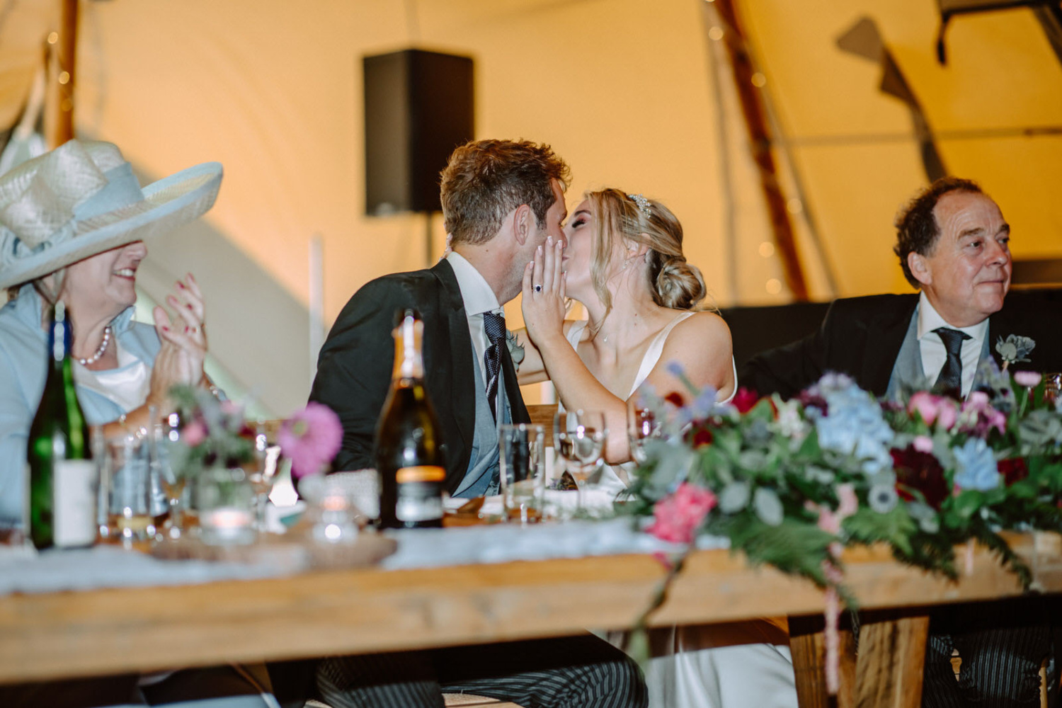 A bride and groom kissing at a wedding reception.