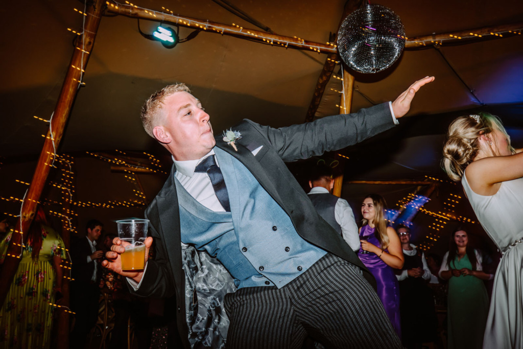 A man dancing with a disco ball at a wedding.