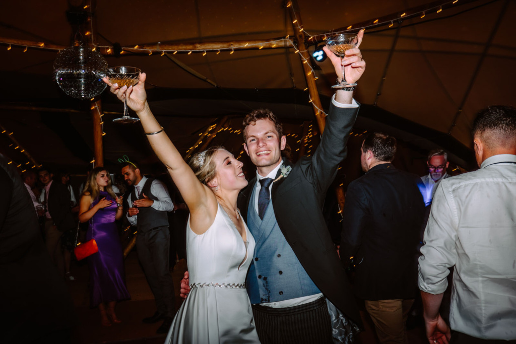 A bride and groom raising their glasses at a wedding party.