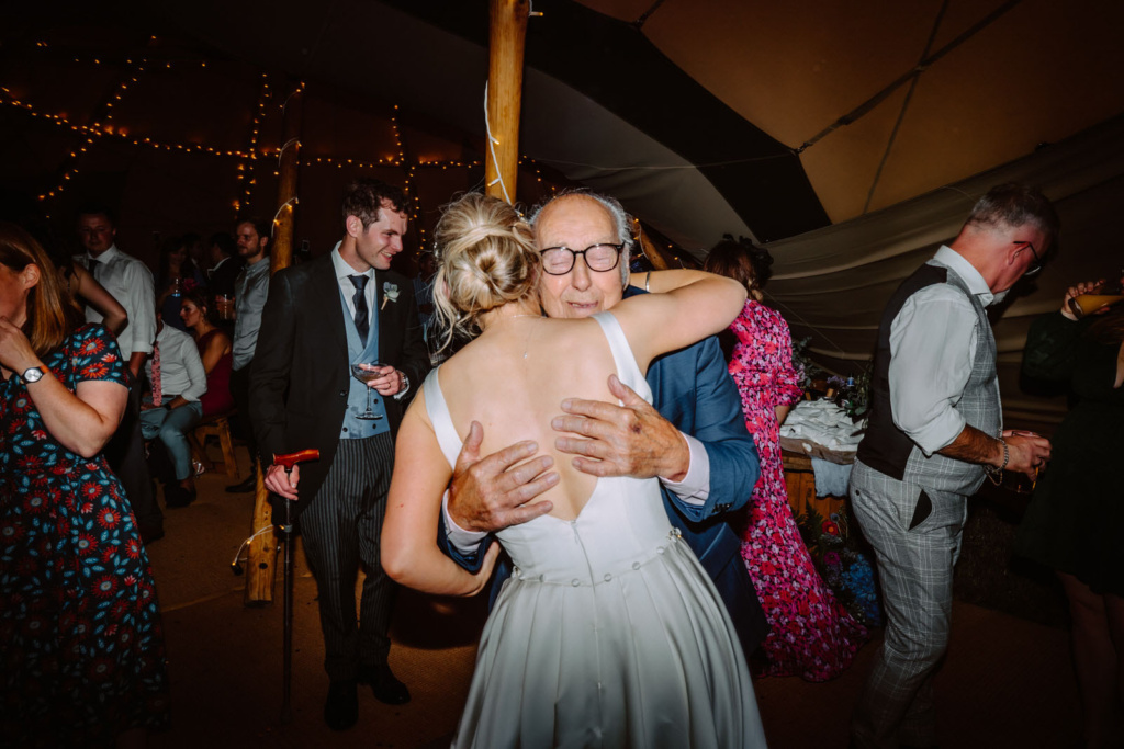 A bride and her granddad hugging at a wedding reception.