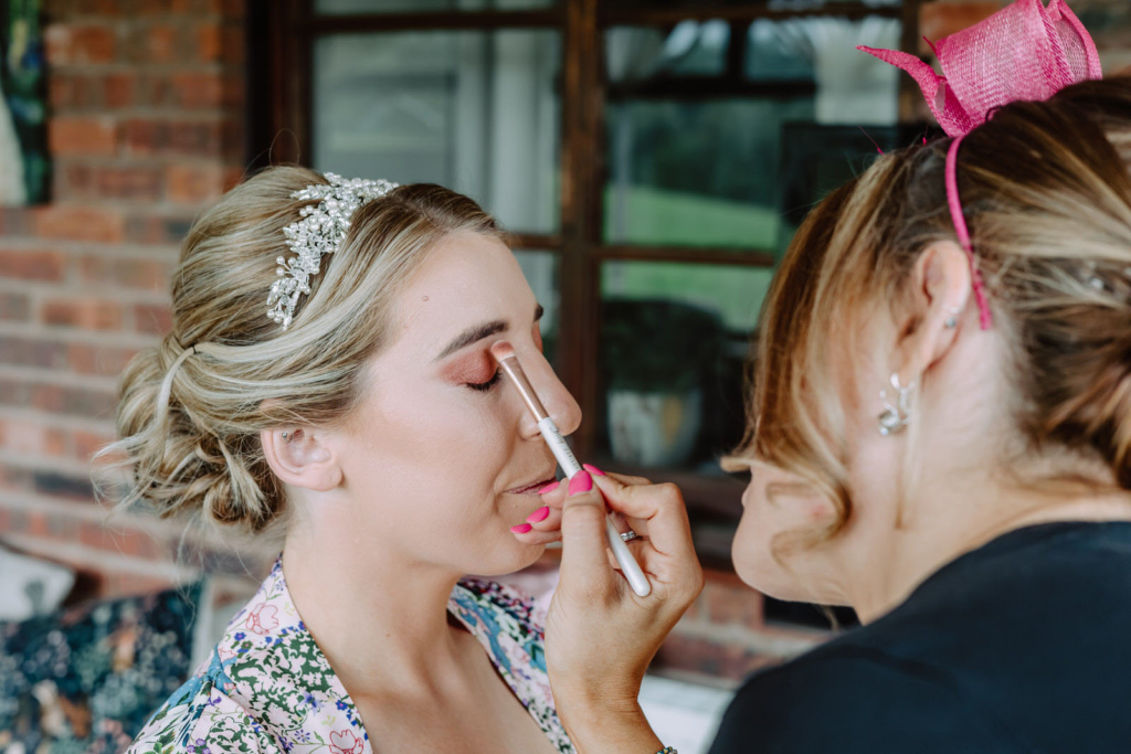 A woman applying makeup bor bride.