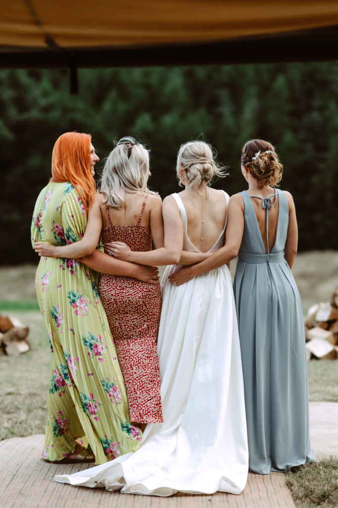 Four bridesmaids hugging in front of a tent.