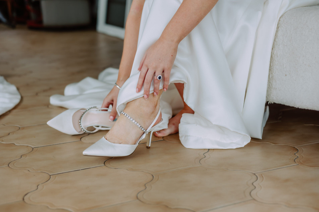 A bride tying her shoes on the floor.