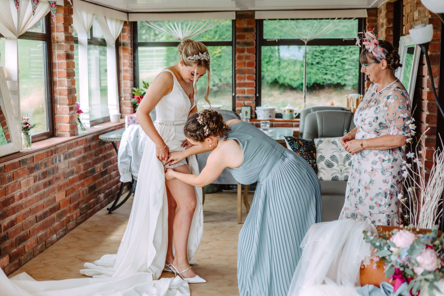 A bride putting on her wedding dress in a room.