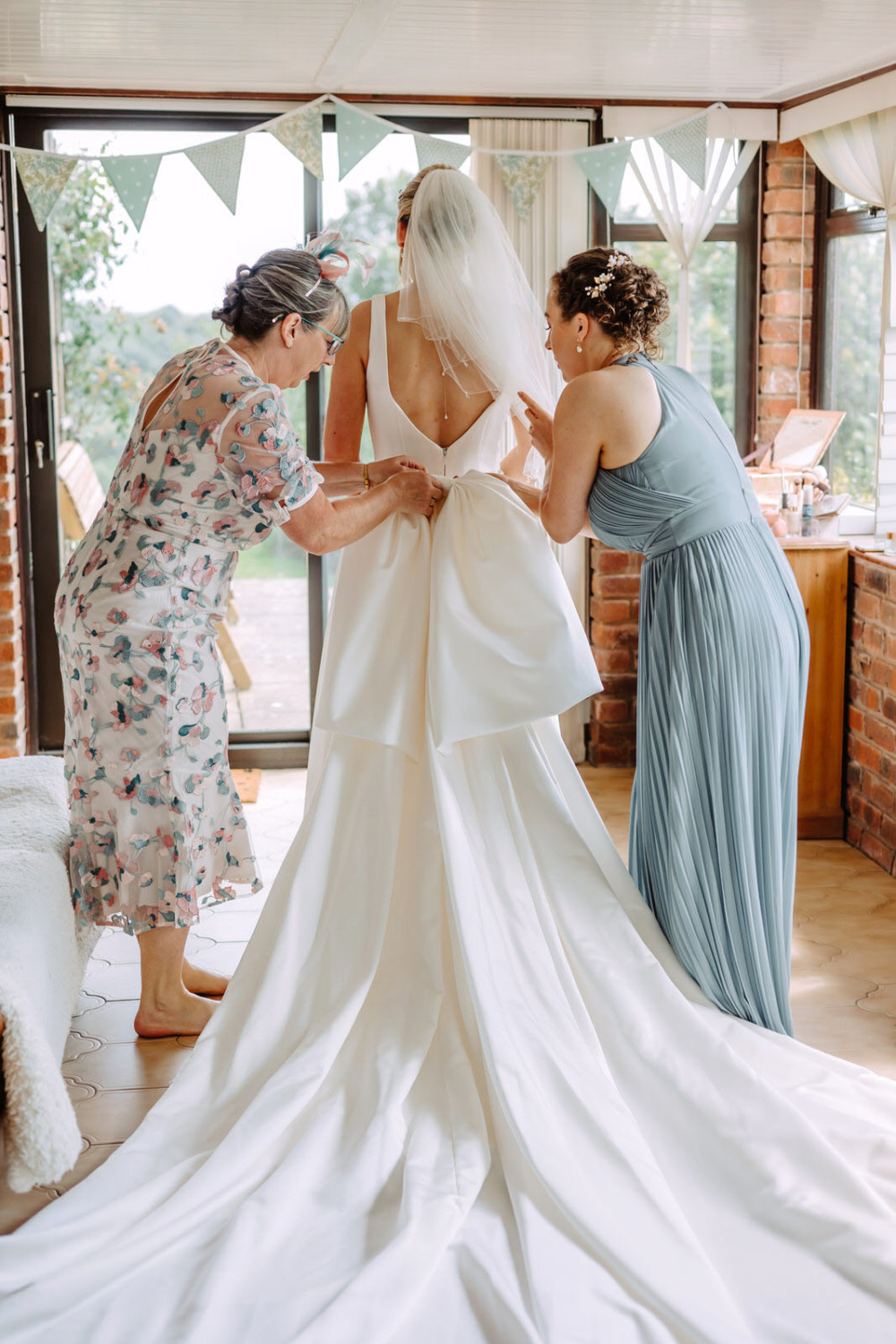 A magnificent bow has been attached to the wedding dress by her mum and the bridesmaid.