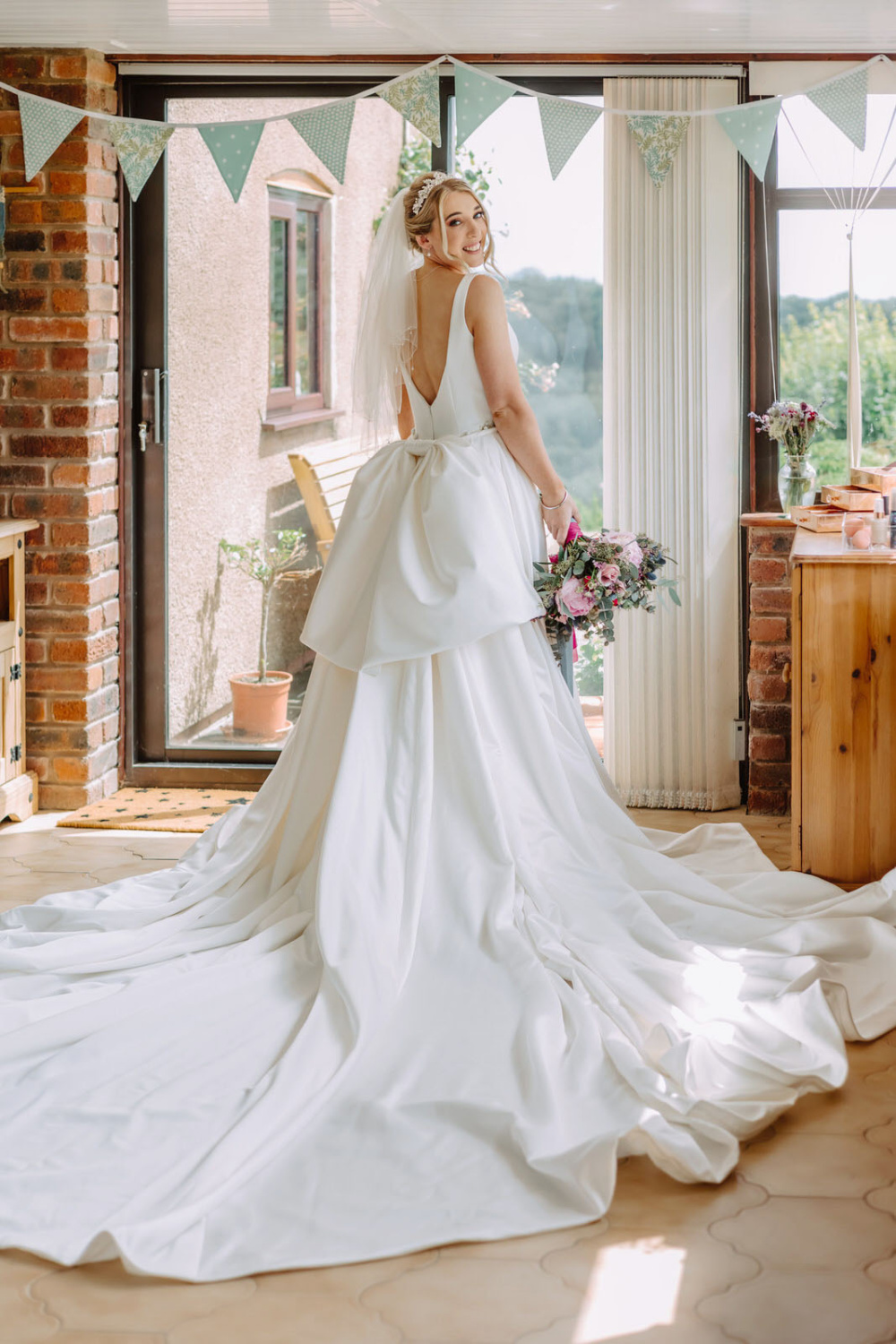 A bride in a wedding dress standing in front of a window.