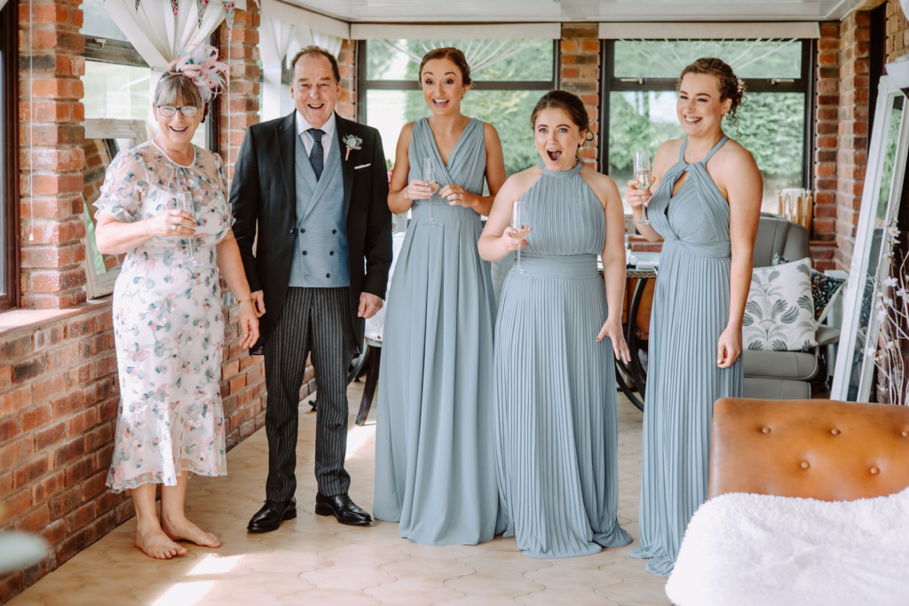 A group of bridesmaids and groomsmen standing in a room.