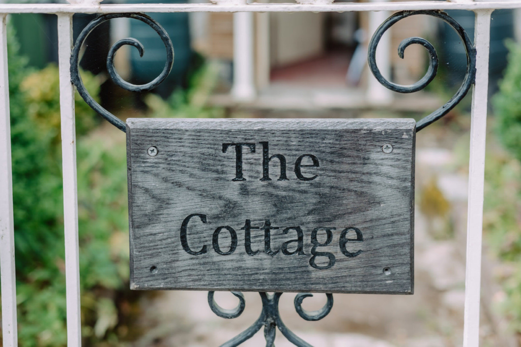 The cottage sign on a gate in front of a house.