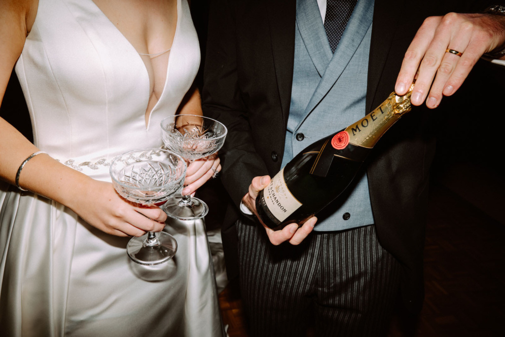 A bride and groom holding a bottle of champagne.