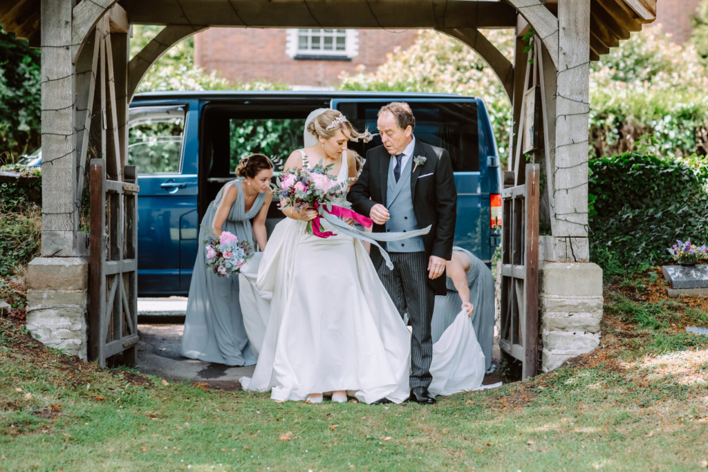 A bride and her dad are standing in front of church.