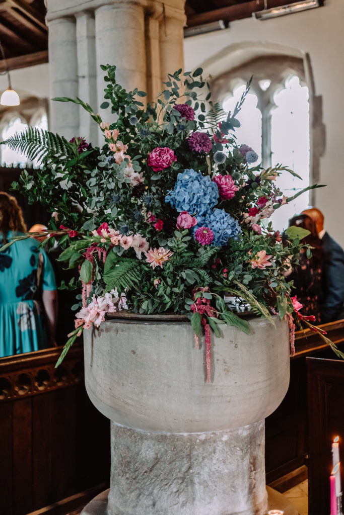 A large pot of flowers sits on a table in a church.