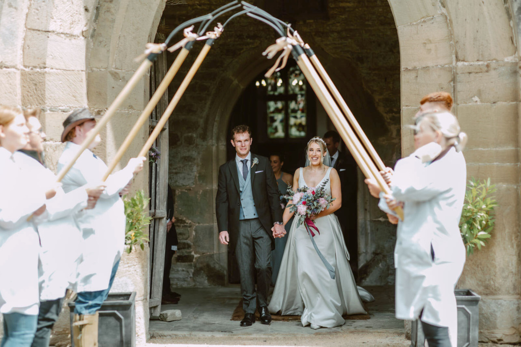 A bride and groom walking down the aisle with forks in their hands.