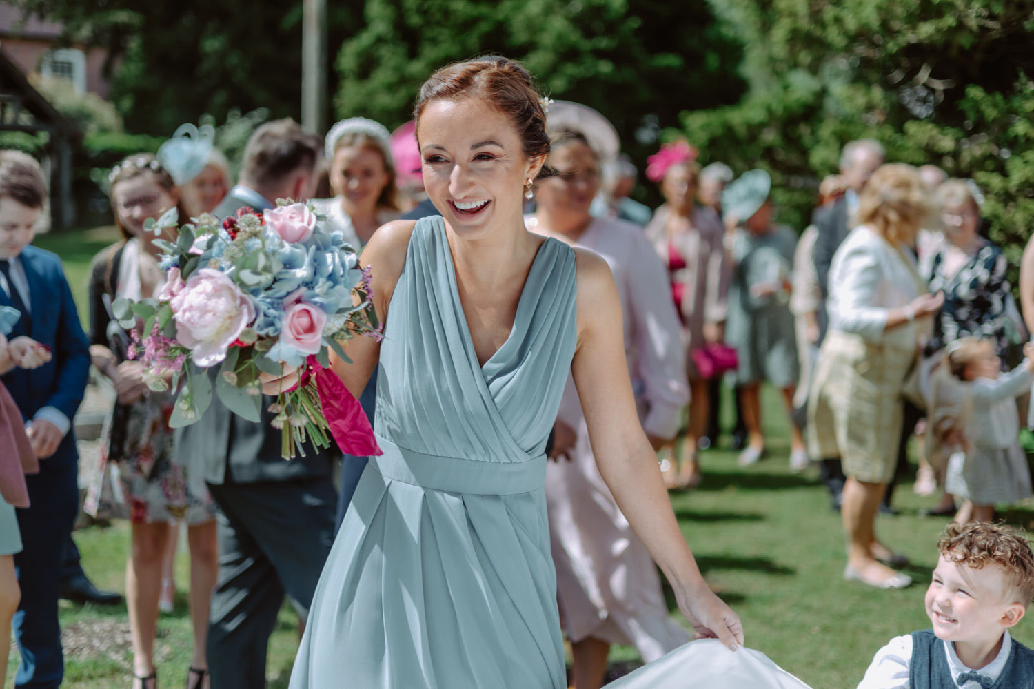 A woman in a blue dress is walking down the aisle with her bridesmaids.