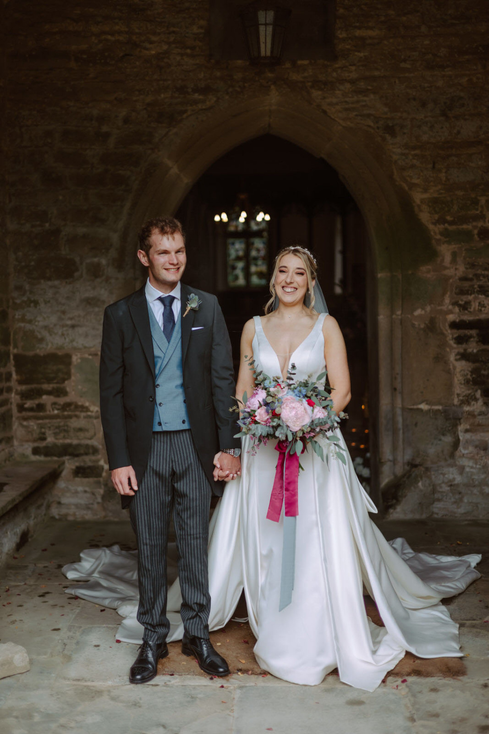 A bride and groom standing in front of an archway.