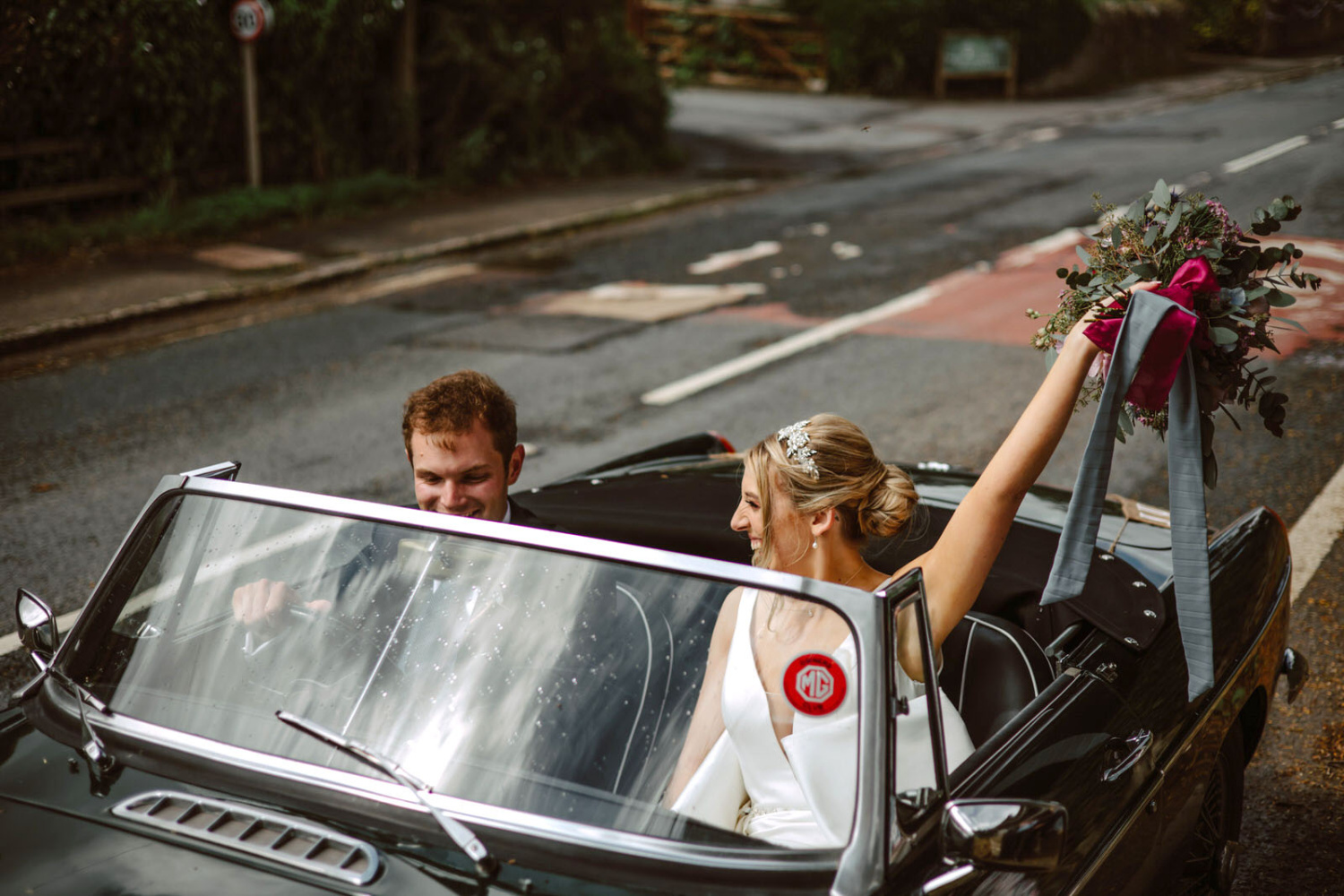 A bride and groom in a classic wedding car.