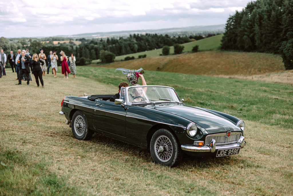 A classics car is parked on a grassy field.