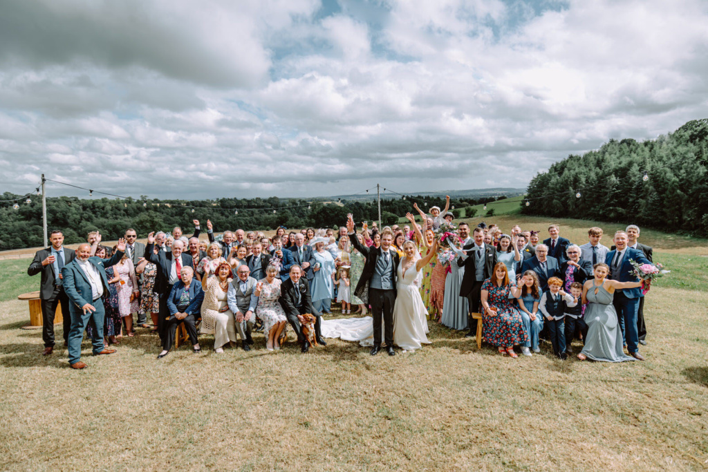 A wedding guests posing for a photo in a field.