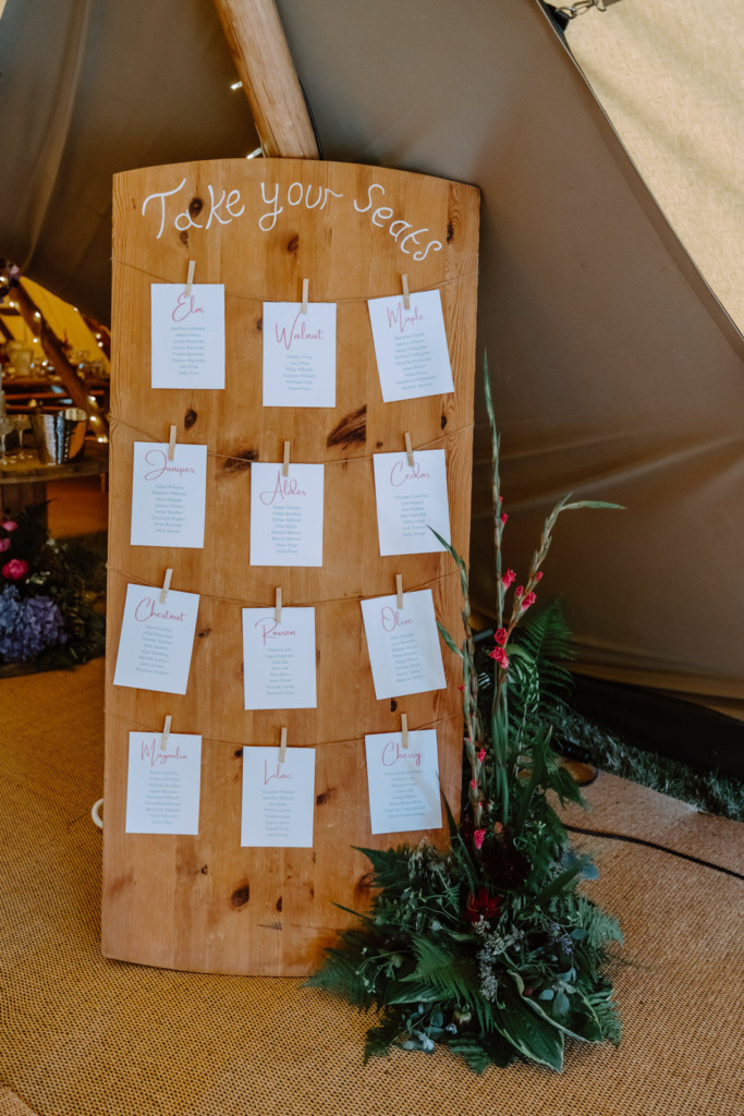 A wooden board with a place card on it in front of a teepee.