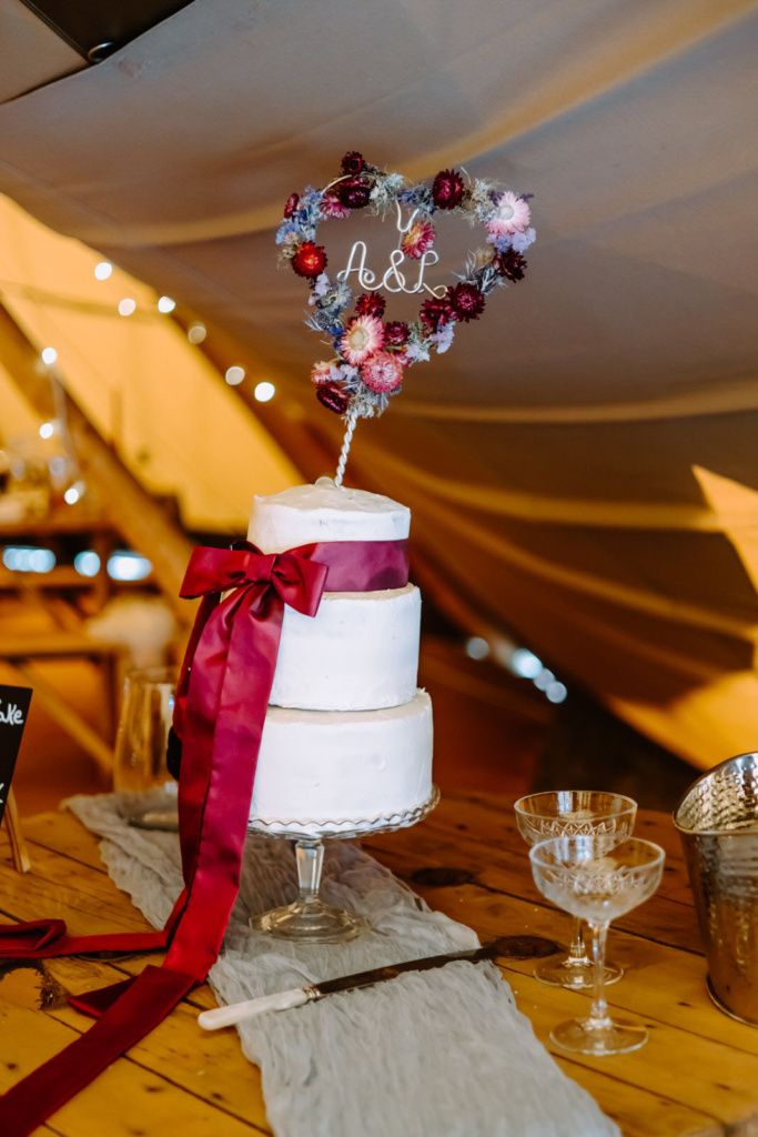 A wedding cake is sitting on a table in a tent.